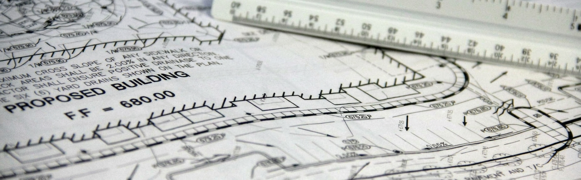 Detailed close-up of architectural blueprints with scale ruler, showing building plans and measurements.